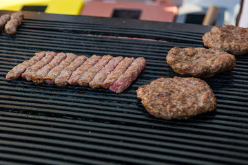 Delicious minced meat cevapcici and pleskavice on a grill.