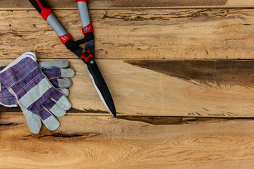 Garden scissors and safety gloves on wooden background with copy space.Garden and home topic: gardening and landscaping service concept