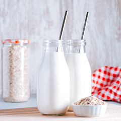 Non dairy oat milk in glass jars with reusable metal straws. Healthy vegan milk alternative still life, copy space. Substitute for traditional cow milk with oat flakes, healthy lifestyle concept