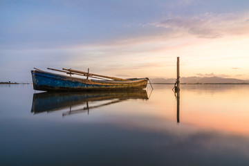 Tranquil scene of a old fishing boat at pink sunset