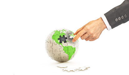 Create your own world or Your own way concept, Earth jigsaw puzzle with green world map missing one piece of jigsaw and businessman hand holding the missing piece of jigsaw on white background