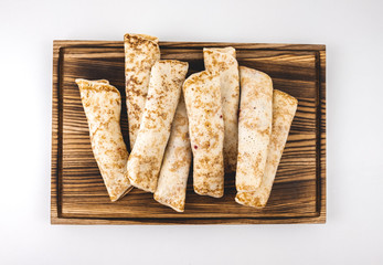 Frozen stuffed pancakes on a wooden board isolated on white background.
