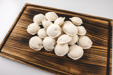 Frozen dumplings on a wooden board isolated on a white background.