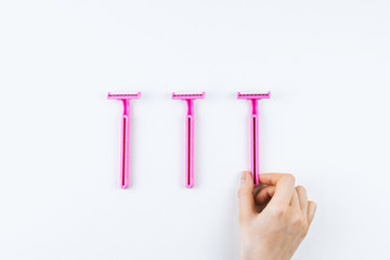 Female hand takes pink disposable razor for hair removal isolated on white background