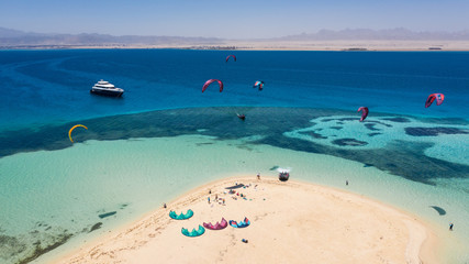 Aerial view of a yacht and a beautiful island and many kitesurfers on the Red Sea in Egypt