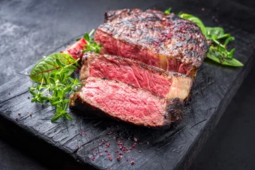 Wandcirkels tuinposter Barbecue dry aged wagyu entrecote beef steak roast with lettuce and tomatoes as closeup on a charred wooden board © HLPhoto