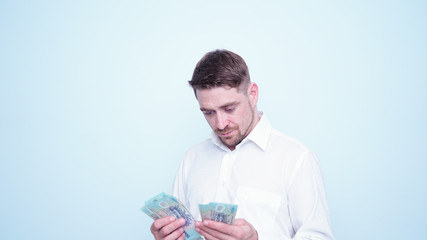 Emotional funny guy in white shirt counting vietnamese money.Portrait of young man taking Vietnam Dong money on his hand with happy emotions and smile on his face