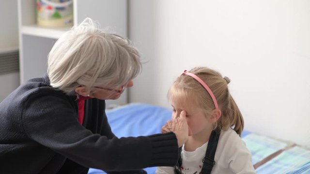Grandmother and granddaughter play together. Grandmother paints her face with children's makeup.