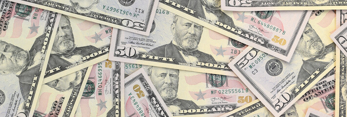 Many US fifty dollar bills on flat background surface close up. Flat lay top view. Abstract...