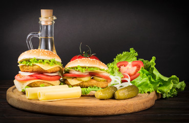 wo tasty burgers on wooden board and black background