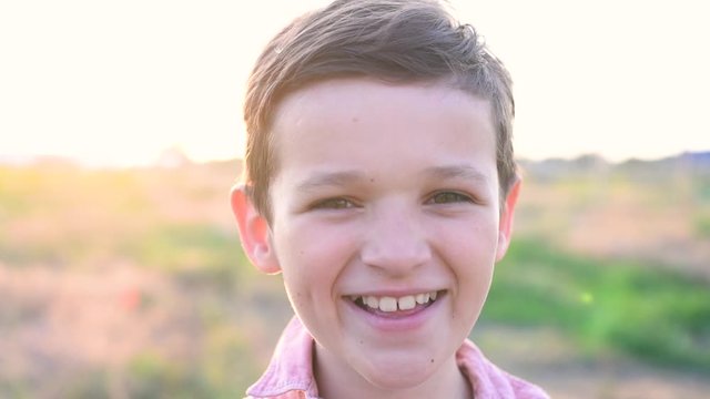 Handsom brunette boy stays and smiling in field