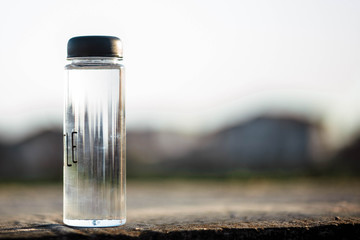 Water bottle. Mug. Water bottle lying on concrete and behind it a blurred background. Coffee. It's...