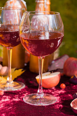 Two glasses of red wine, half an apple, figs on a velvet table.
