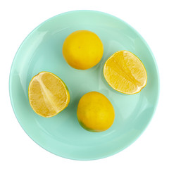 two whole yellow-green grapefruits and two halves lie on a turquoise round plate on a white background. Isolate