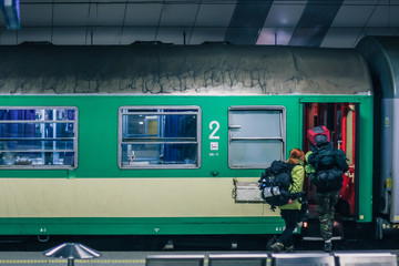 Exterior of Polish green sleeping train wagon, standing on a platform on a train station in Krakow with backpackers going aboard. Backpack traveling with a train.