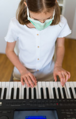 Little girl learning the piano during quarantine.