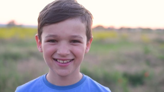 Handsom brunette boy stays and smiling in field