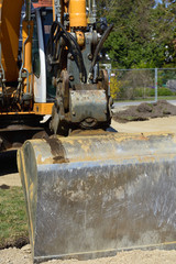 03/28/2020, Friedberg, Bavaria in Germany: partial shot of an excavator with an excavator bucket in portrait format outdoors on a construction site on a spring day