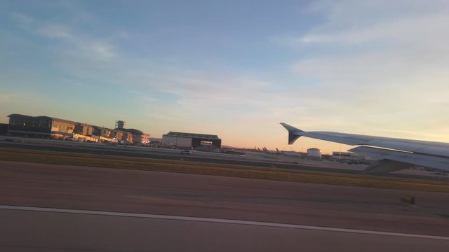 Wing side view of plane taking off from Los Angeles International Airport, LAX at sunset