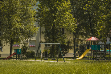 Obraz na płótnie Canvas Children playground with wooden objects in the middle of a socialistic style block neighbourhood. Visible slides and swings.