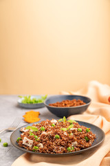 Quinoa porridge with green pea and chicken on ceramic plate on a gray concrete background. Side view, copy space.
