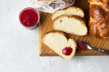 Challah bread or cozonac on a wooden board, light grey stone background. Shabbat, Jewish traditional bread. Easter bakery. Top view.