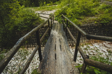 Fototapeta na wymiar Slippery and dangerous wooden bridge for pedestrians in a countryside. Path leading through the woods over the wooden bridge