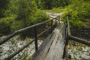 Fototapeta na wymiar Slippery and dangerous wooden bridge for pedestrians in a countryside. Path leading through the woods over the wooden bridge
