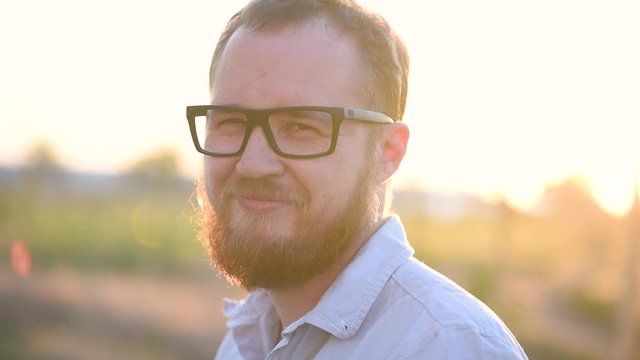 Handsome man with beard in glasses on the background of field