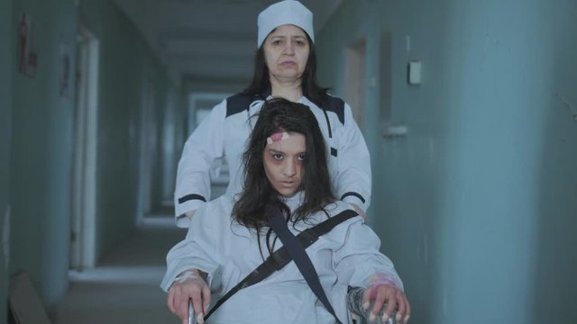 Female Nurse Pushing Patient In The Wheelchair Through The Hospital Corridor