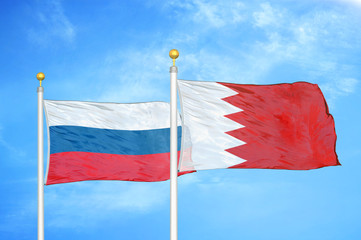 Russia and Bahrain  two flags on flagpoles and blue cloudy sky