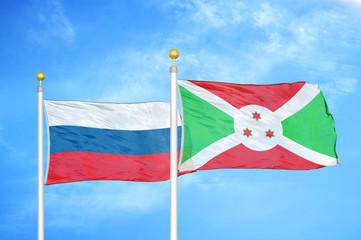 Russia and Burundi  two flags on flagpoles and blue cloudy sky
