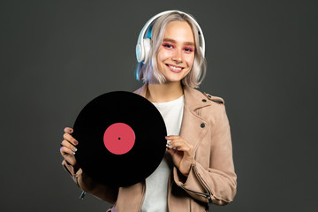 Mysterious hipster teenager listening to music with headphones. Portrait of millennial pretty girl...