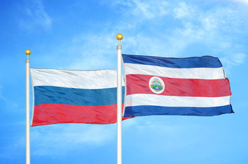 Russia and Costa Rica two flags on flagpoles and blue cloudy sky