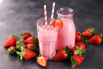 Glass of fresh strawberry shake, smoothie or milkshake and fresh strawberries on table. Healthy...