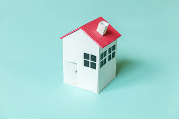 Simply design with miniature white toy house isolated on blue pastel colorful trendy background. Mortgage property insurance dream home concept. Flat lay top view copy space.