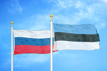 Russia and Estonia two flags on flagpoles and blue cloudy sky