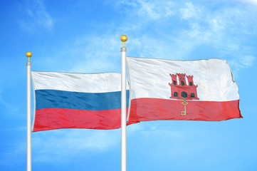 Russia and Gibraltar two flags on flagpoles and blue cloudy sky