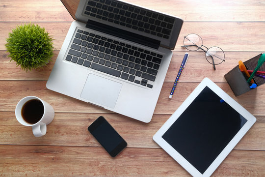 top view of digital tablet, laptop, pen and notepad on wooden table 