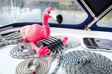 Pink flamingo toy and sailing yacht ropes perfectly coiled near it's clamps. Largs, Scotland.