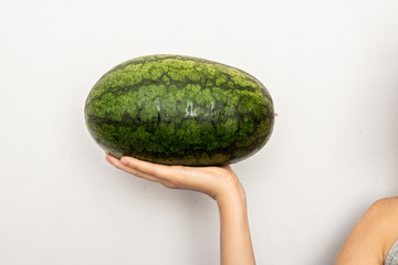 Female hands holding a ripe watermelon on white background.