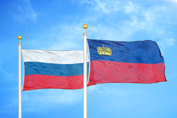 Russia and Liechtenstein two flags on flagpoles and blue cloudy sky