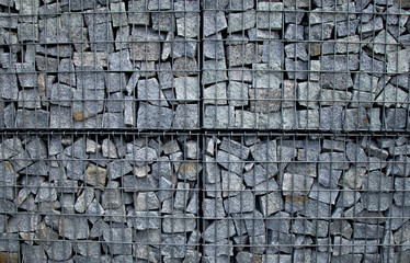 A wall of stones stacked in wire mesh. Masonry in an iron grid