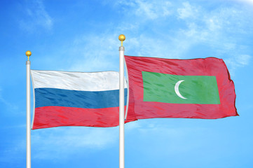 Russia and Maldives two flags on flagpoles and blue cloudy sky