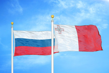 Russia and Malta two flags on flagpoles and blue cloudy sky