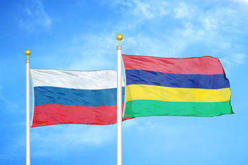 Russia and Mauritius two flags on flagpoles and blue cloudy sky