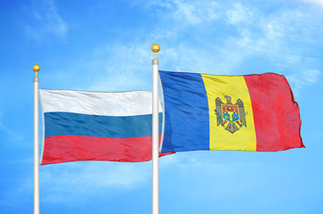 Russia and Moldova two flags on flagpoles and blue cloudy sky