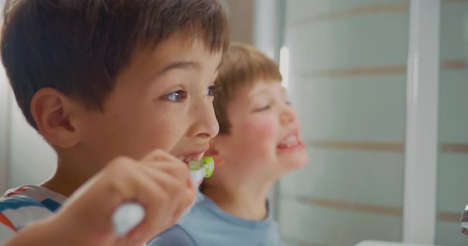 Cheerful Kids In Pyjamas Brushing Their Teeth And Having Fun Infront Of The Bathroom Mirror. Close-up Side Shot.