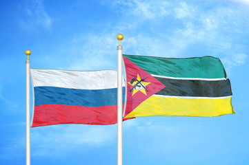 Russia and Mozambique two flags on flagpoles and blue cloudy sky