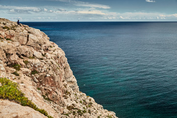 The Landscape of the balearic sea and improbable mountains, azure water, the storm sky, lonely buildings at tops of mountains, sail boat is on background
